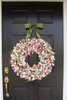 a wreath with pink and white tulips hangs on the front door