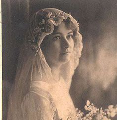 an old black and white photo of a woman wearing a veil with flowers in her hair