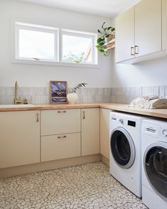 a washer and dryer sitting in a kitchen next to a window with potted plants