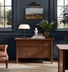 a living room scene with focus on the desk and chair next to the window,