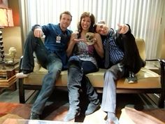 three people sitting on a couch posing for the camera