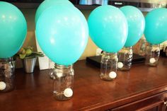 several blue balloons are sitting in mason jars