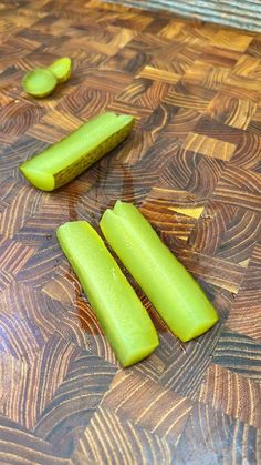 three pieces of cucumber sitting on top of a wooden table next to each other