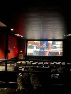 a person sitting in front of a large screen with their feet propped up on the seats