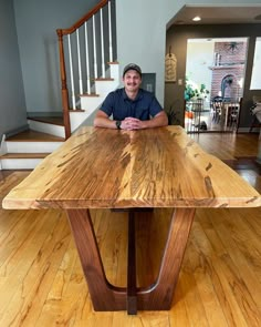 a man sitting at a wooden table in the middle of a room with hardwood floors