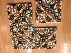 three pieces of decorative tile sitting on top of a wooden floor