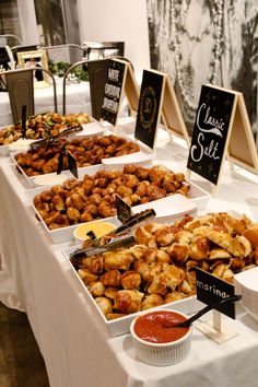 an assortment of food is on display at a buffet table with chalkboards and signs