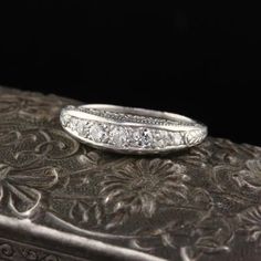 an antique diamond ring sits on top of a silver box