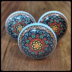 three decorative glass knobs sitting on top of a wooden table