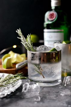 an alcoholic drink with ice and rosemary garnish