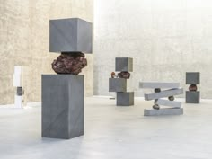 several sculptures are arranged on concrete blocks in the middle of a room with cement walls and flooring