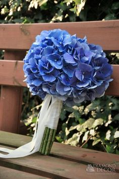 a bouquet of blue flowers sitting on top of a wooden bench