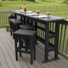 an outdoor bar with three stools on a deck in front of a grassy field