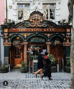 the cross keys pub in london is decorated with potted plants and greenery on either side