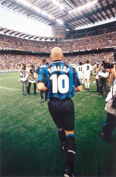 a soccer player walking off the field with his team mates in the stands behind him