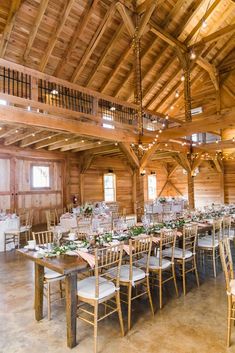 the inside of a large wooden building with tables and chairs set up for an event