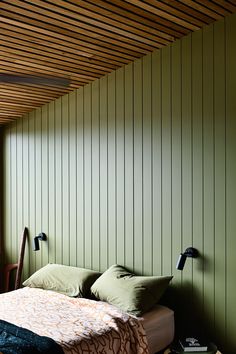 a bed sitting under a wooden ceiling next to a wall with green paint on it