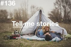 a woman laying on top of a blanket next to a tent with the words tell me stories