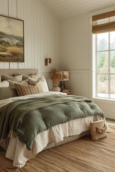 a large bed sitting in a bedroom next to a window covered in blankets and pillows