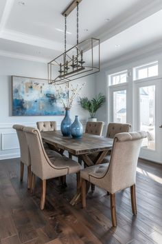 a dining room table with chairs and vases on top of it in front of a large window