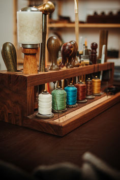 an assortment of sewing thread and spools on a wooden stand