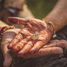 two people holding their hands together with hendi tattoos on them and rings in each hand