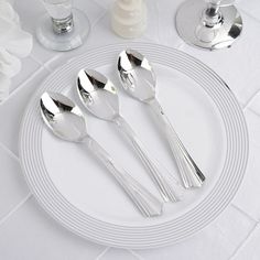 four silver spoons on a white plate with flowers in the background