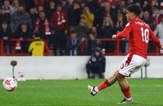 a man kicking a soccer ball on top of a field