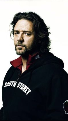 a man with long hair wearing a black sweatshirt and red hoodie, looking at the camera