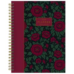 a planner book with red flowers and green leaves on the cover, in front of a black background