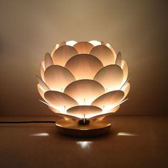 a light that is on top of a wooden table with a lamp in the shape of a flower