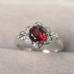 ◆The ring draws inspiration from the polaris. Hand-finished in Sterling sliver, this piece features a round shaped garnet . Clear zirzons decorate around the main stone. An extremely simple celestial ring that you cannot miss. ◆ Production Description: Main stone Type: Garnet Main Stone Shape: Round Main Stone Size:7*7mm(1.68ct) Side stone: CZ Metal: 925 Sterling silver - Other options available in the drop down menu ◆ Customization: √Free for Add Engraving √Other Metal Type Available √Other Gem Elegant Silver Ruby Flower Ring, Sterling Silver Ruby Ring With Gemstone Accents, Silver Garnet Ruby Ring With Center Stone, Round Garnet Jewelry With Halo Setting, Ruby Birthstone Ring With Gemstone Accents, Silver Garnet Ring, Nontraditional Engagement Rings, Garnet Wedding Rings, Garnet Wedding