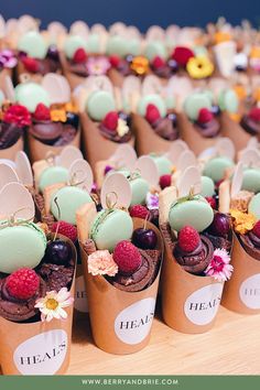 there are many cupcakes in paper cups with fruit on the top and flowers around them