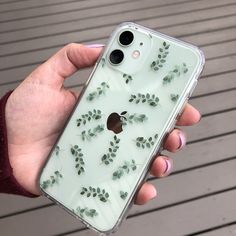 a person holding an iphone case with leaves on it