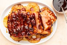 a white plate topped with french toast covered in bbq sauce and pineapple slices