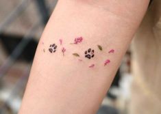 a person with a tattoo on their arm that has pink and green flowers all over it