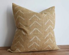 a brown and white pillow sitting on top of a wooden floor next to a wall