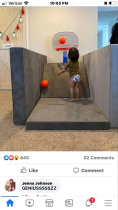 a toddler playing with an inflatable basketball hoop on the floor next to a wall