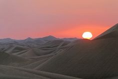 the sun is setting over some sand dunes