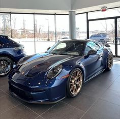 two blue sports cars are parked in a showroom