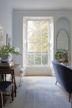 a living room filled with furniture and a large window next to a blue chair on top of a rug