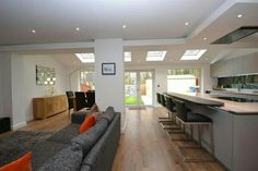 a living room filled with furniture next to a kitchen and an open concept dining area