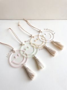 three white tasselled earrings with the words happy and smiley on them, hanging from strings