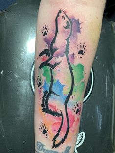 a person with a colorful tattoo on their arm and leg that has watercolor paint splatters all over it