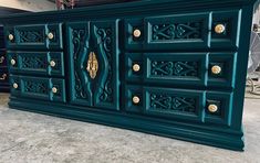 a large green cabinet with ornate carvings on it's sides and gold knobs