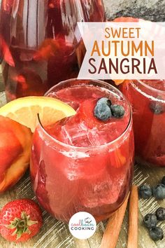 two glasses filled with sangria sitting on top of a table next to sliced fruit