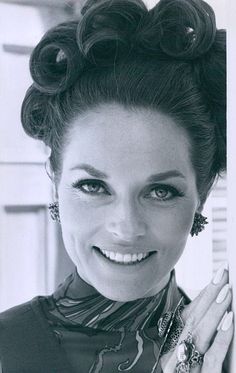 a black and white photo of a woman with her hands on her chest smiling at the camera