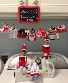 two elfs hanging from clothes line in front of washing machine