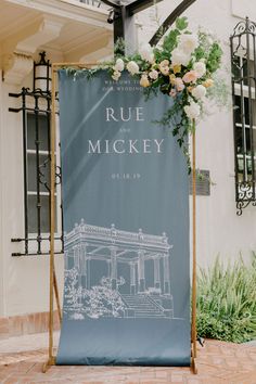 a blue and white banner with flowers on it sitting in front of a brick building