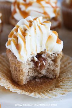 cupcakes with white frosting and caramel swirl on top sitting on a plate